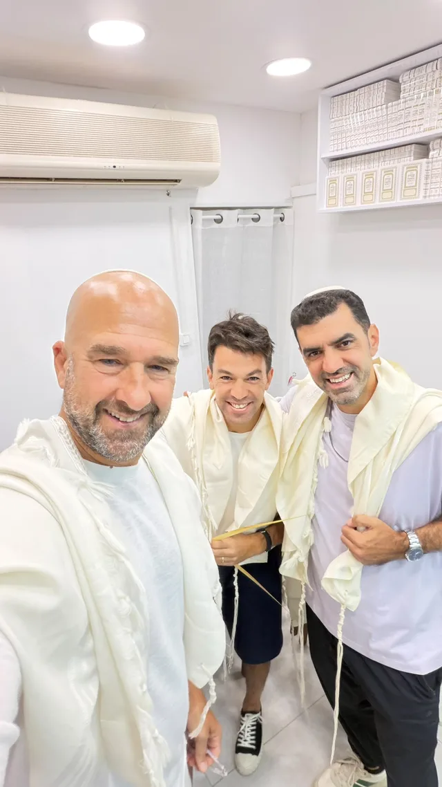 שלושה מתפללים מחייכים בטליתות