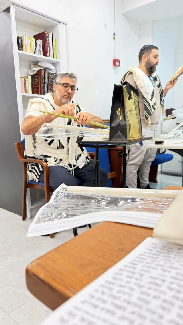 מתפלל יושב עם לולב ליד סידור פתוח