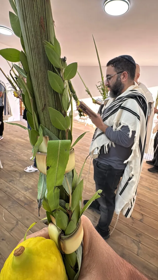 אתרוג ולולב מקרוב, מתפלל בטלית ברקע