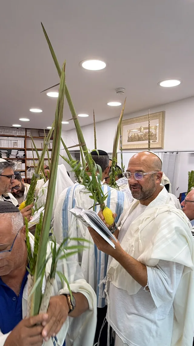 מתפללים עם לולב ואתרוג בין ארונות הספרים