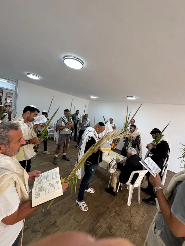 מתפללים בטליתות עם לולבים וסידורים